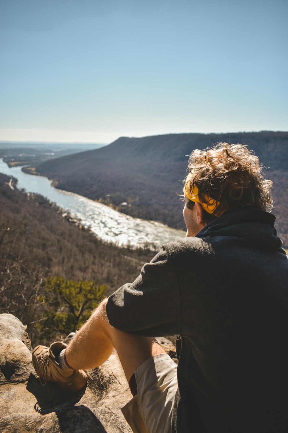 a man sitting on top of a rock next to a river