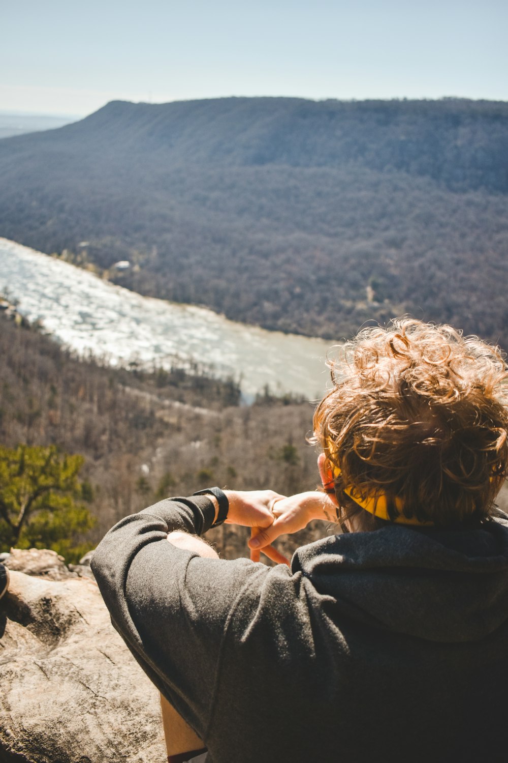 a person sitting on top of a rock looking at a river