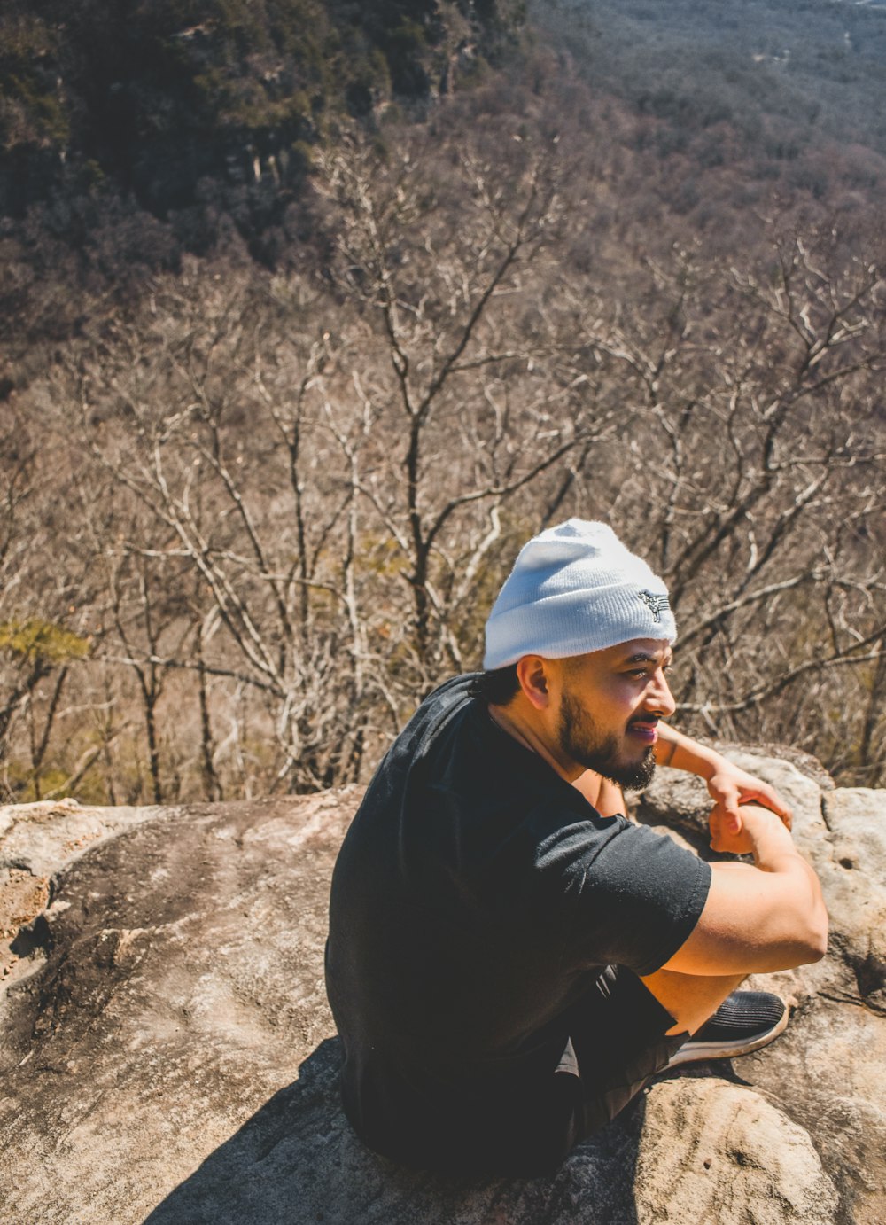 a man sitting on top of a rock next to a forest