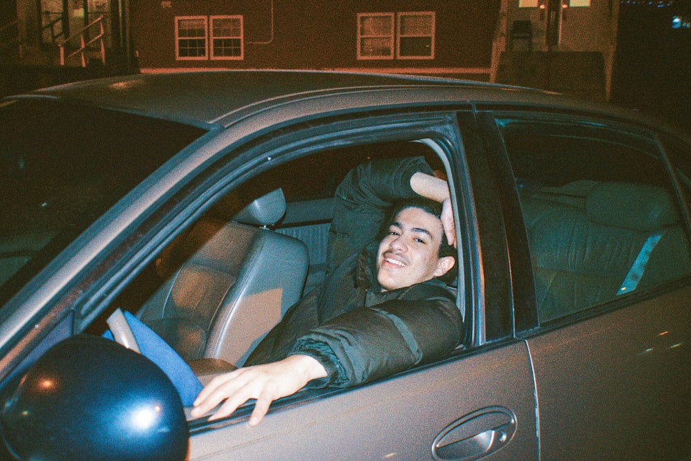 a man sitting in a car with his head out the window