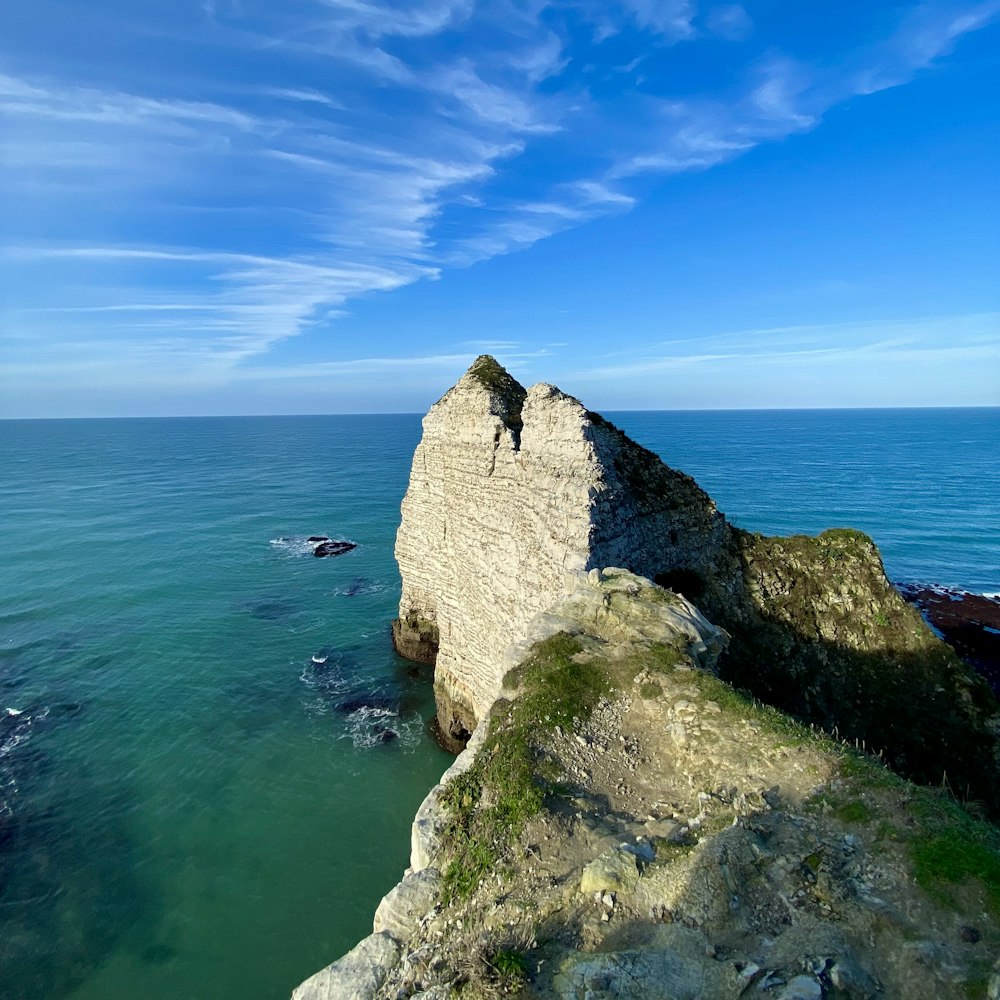 a person standing on top of a large rock near the ocean