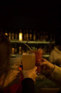 a group of people holding up drinks at a bar