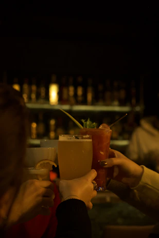 a group of people holding up drinks at a bar