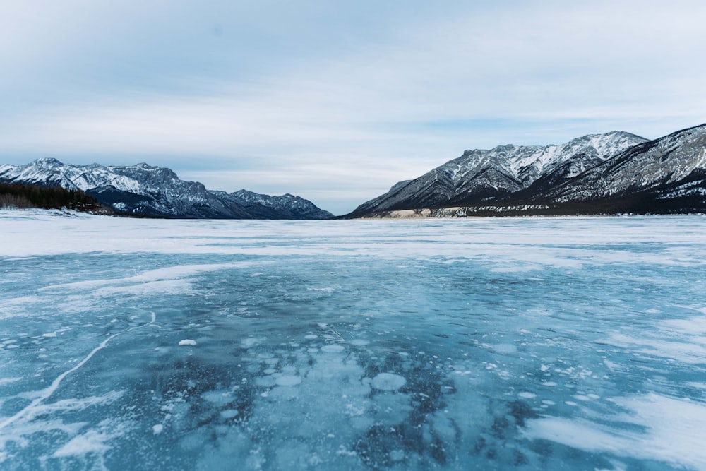 a frozen lake with mountains in the background