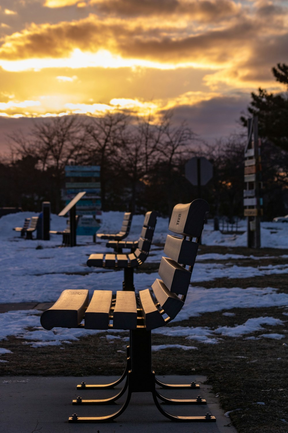 a row of benches sitting on top of a snow covered field