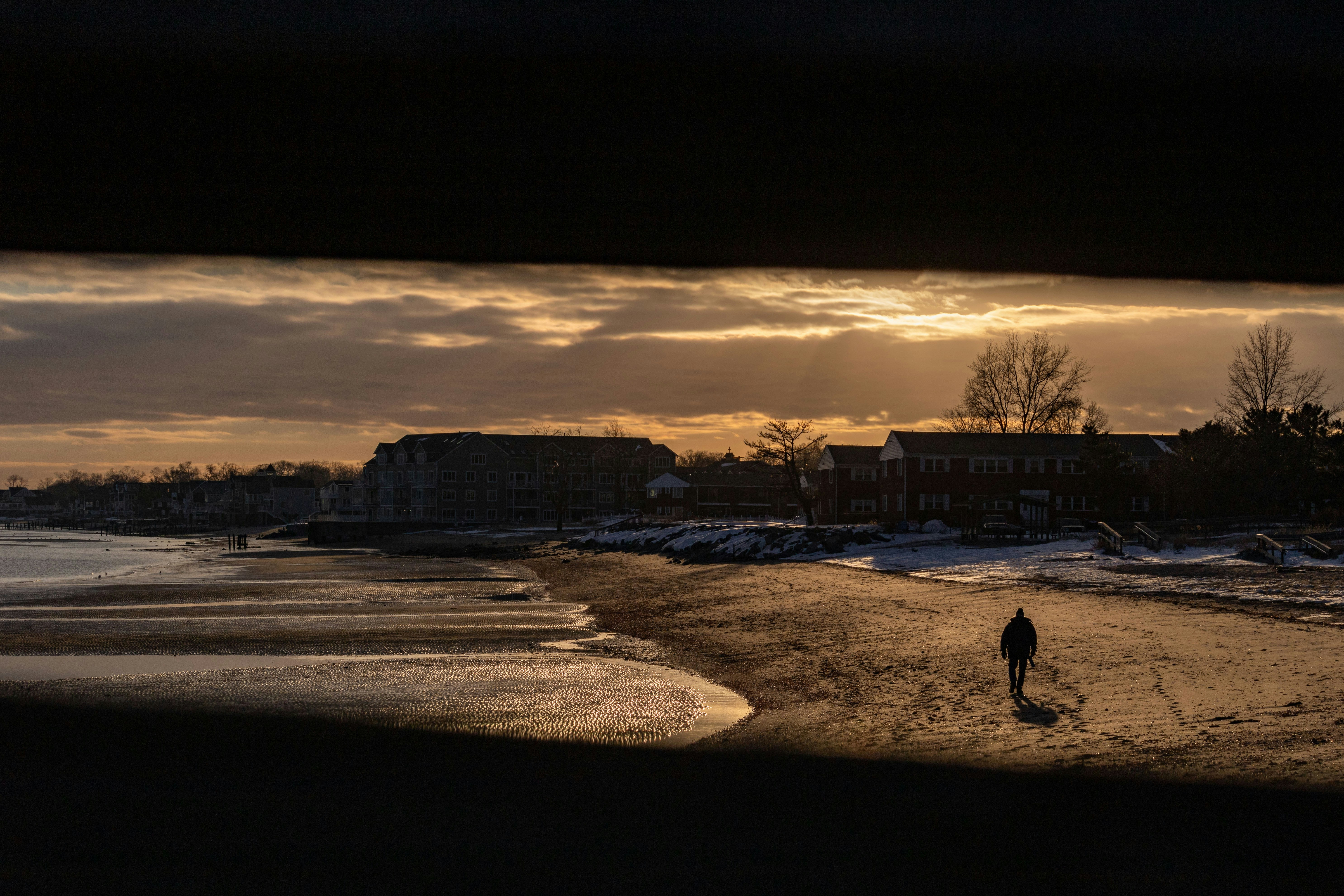 a person walking on a beach at sunset
