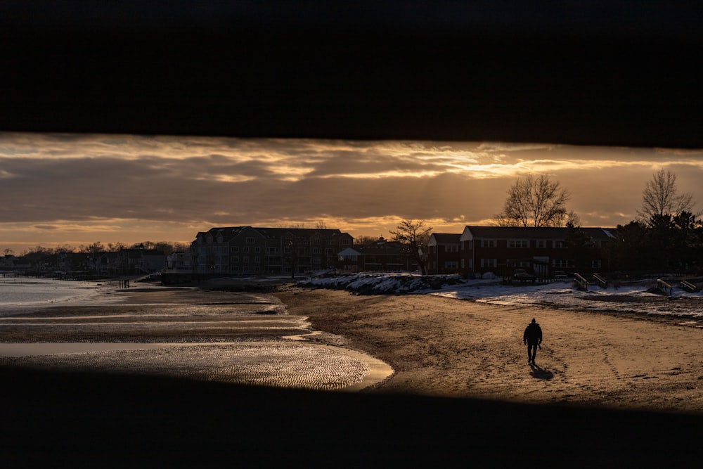 Una persona che cammina su una spiaggia al tramonto