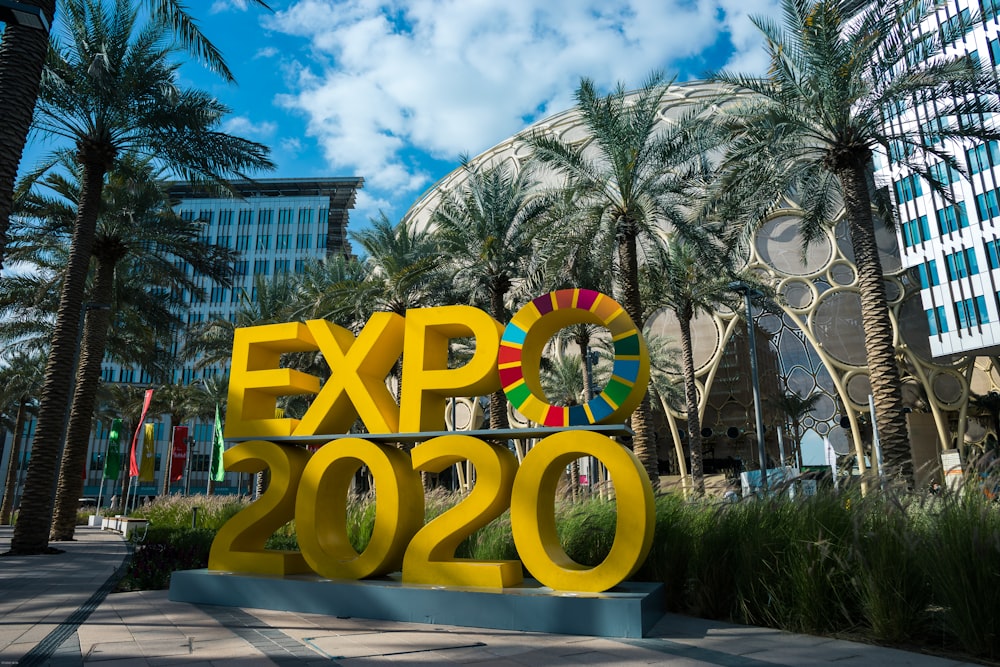 a sign that says expo expo in front of palm trees