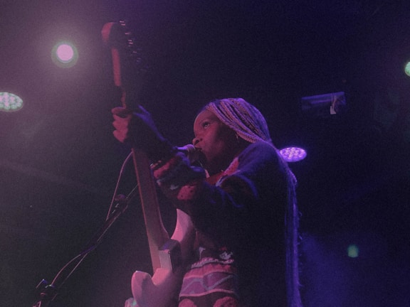 Liam Boorse playing guitar on stage under colorful psychedelic lights.