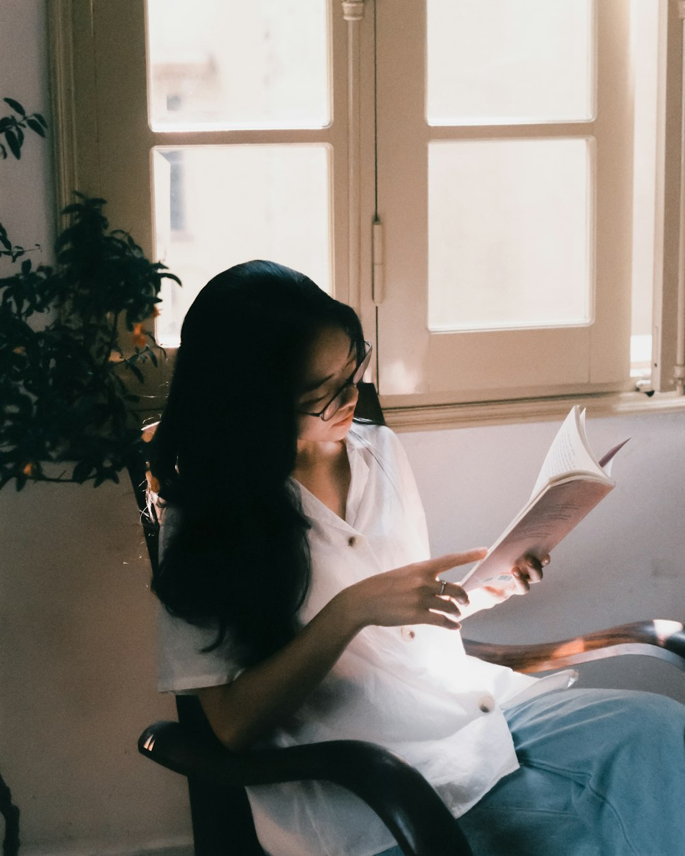 a woman sitting in a chair reading a book