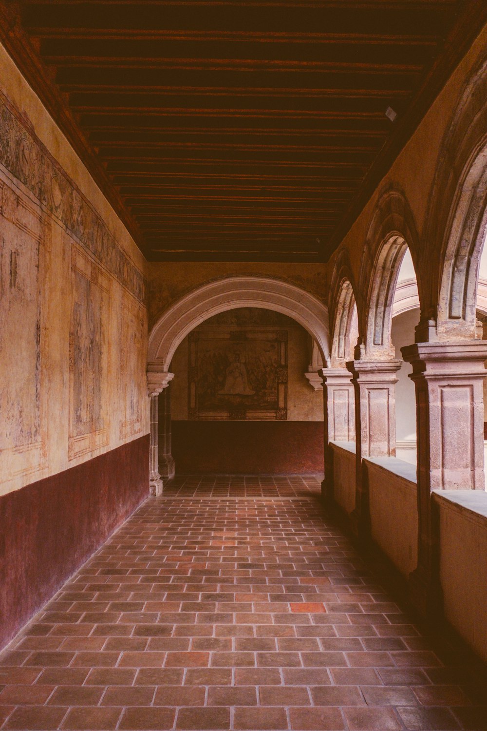 a long hallway with arches and a clock on the wall