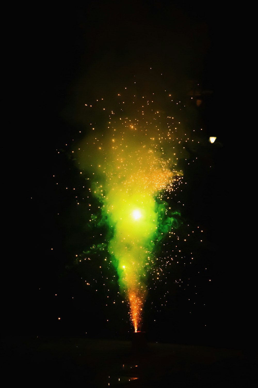 a green and yellow firework in the night sky