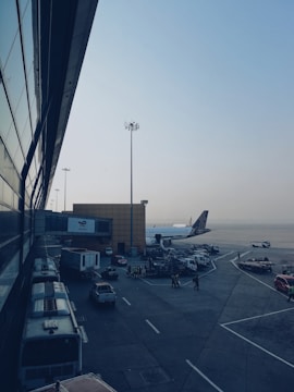 An aircraft on the tarmac with a backdrop of a bustling airport terminal.