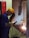 A worker engaged in welding, wearing a yellow safety helmet, protective gloves, and a face shield. Sparks are visible as the welding process takes place inside a workshop. The worker is standing at a metal workbench, carefully operating a welding tool.