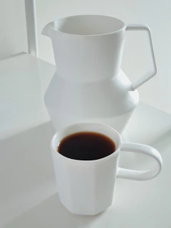 A minimalist coffee setup with a sleek ceramic mug and freshly brewed coffee, bathed in natural light.