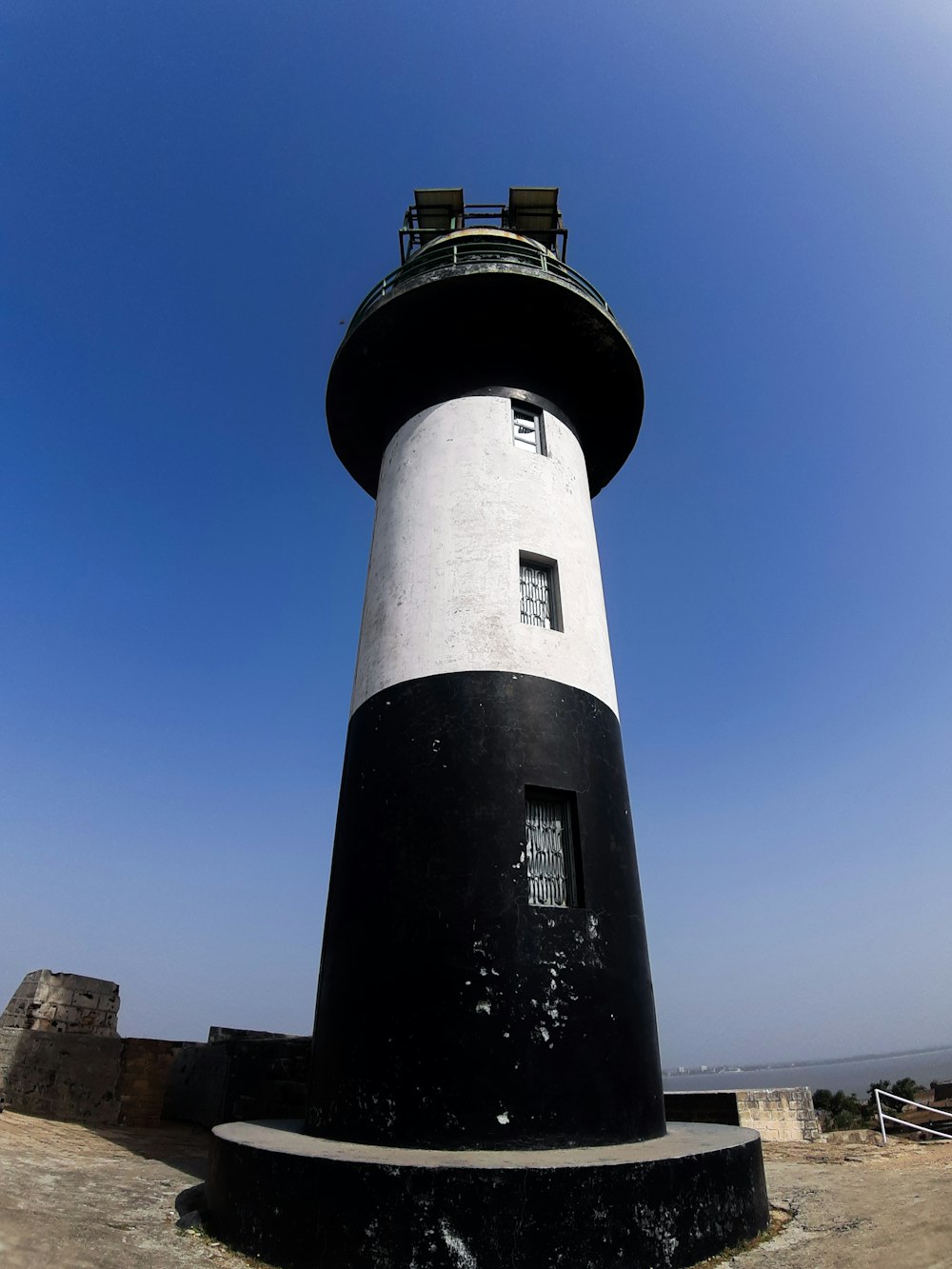 a black and white lighthouse with a blue sky in the background