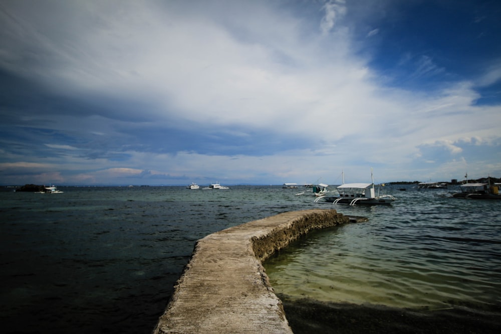 a dock with boats in the water and a cloudy sky