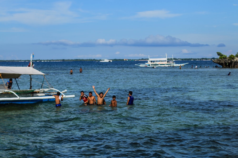 Un gruppo di persone in piedi nell'oceano accanto a una barca