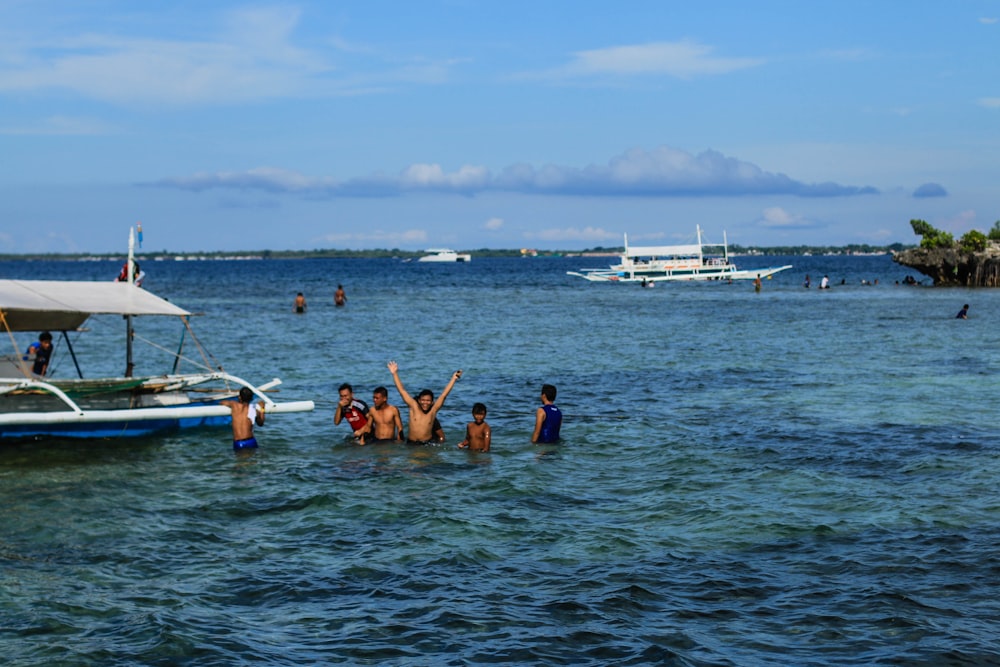 a group of people standing in the ocean next to a boat