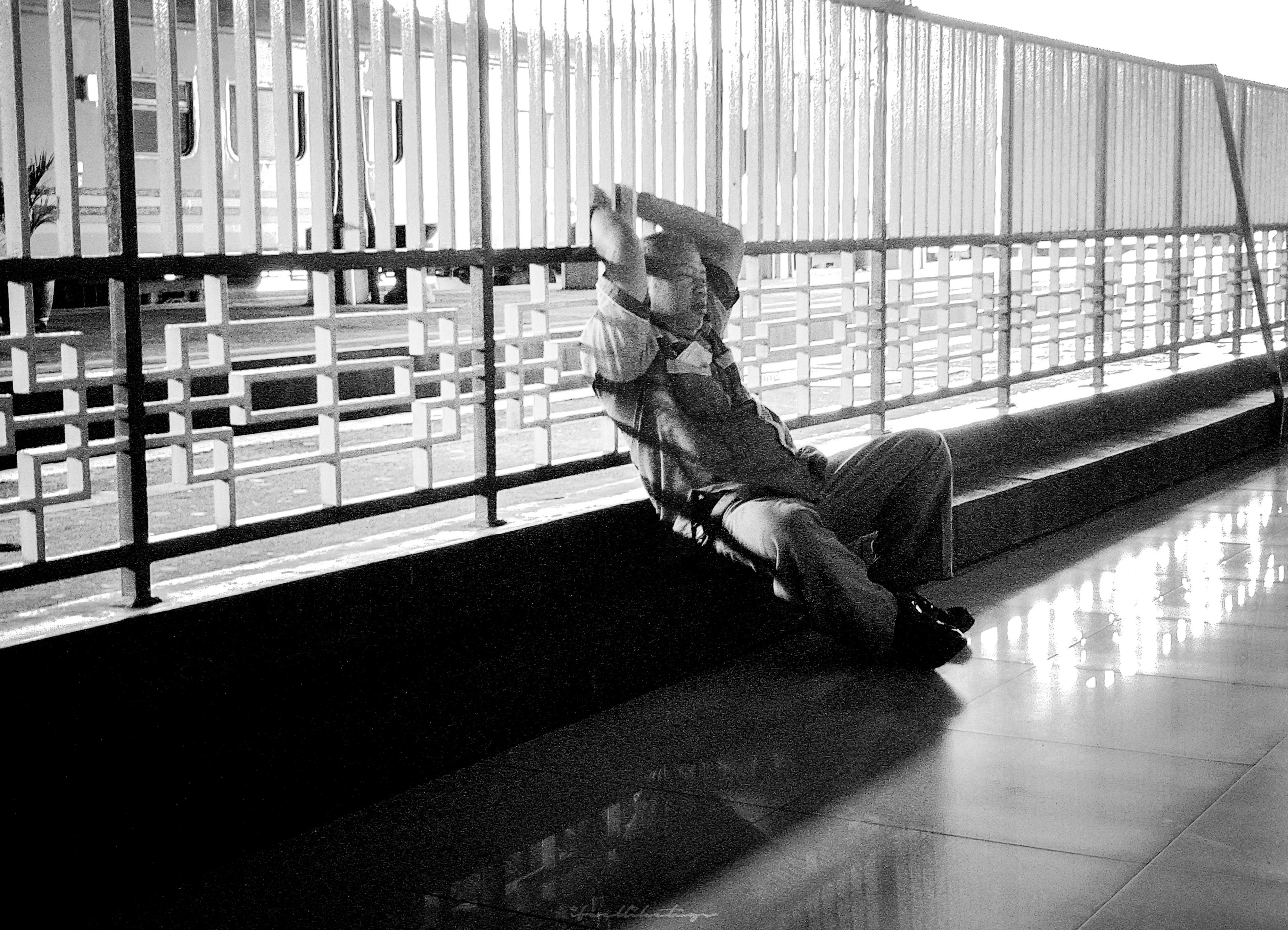 a man sitting on a bench next to a fence