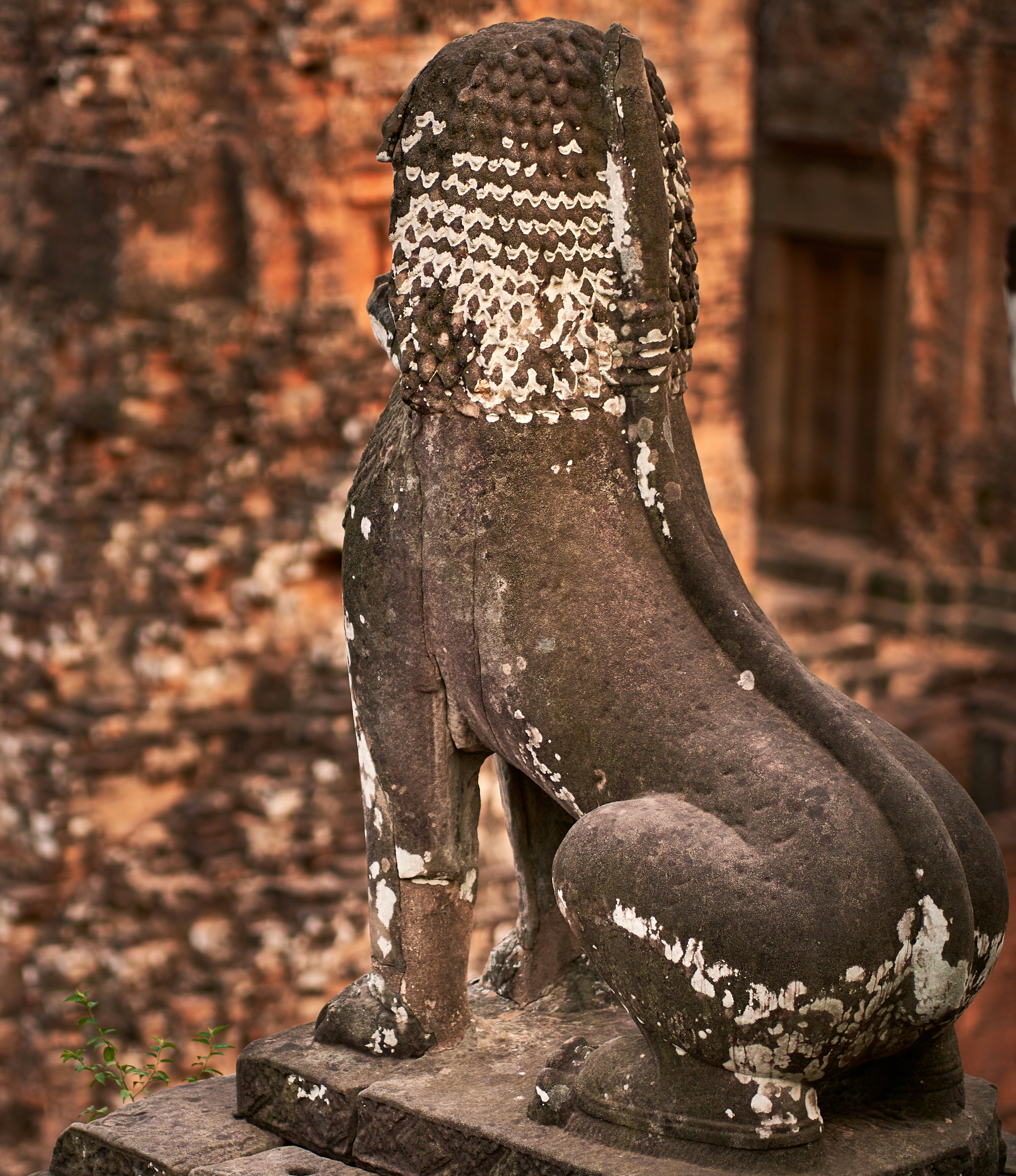 a stone statue of a seated dog in front of a brick wall