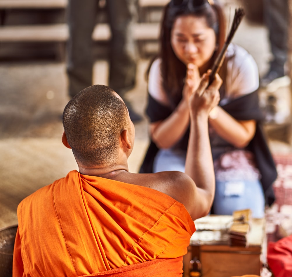 a man in an orange robe sitting next to a woman