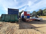 A fleet of blue cargo trucks lined up at a busy logistics hub under a clear sky.