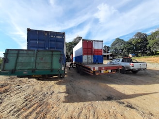 A fleet of trucks parked in a logistics yard under a clear blue sky.