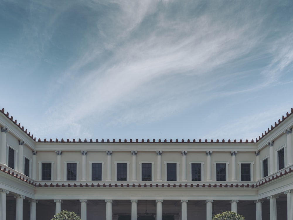 a large white building with columns and a sky background