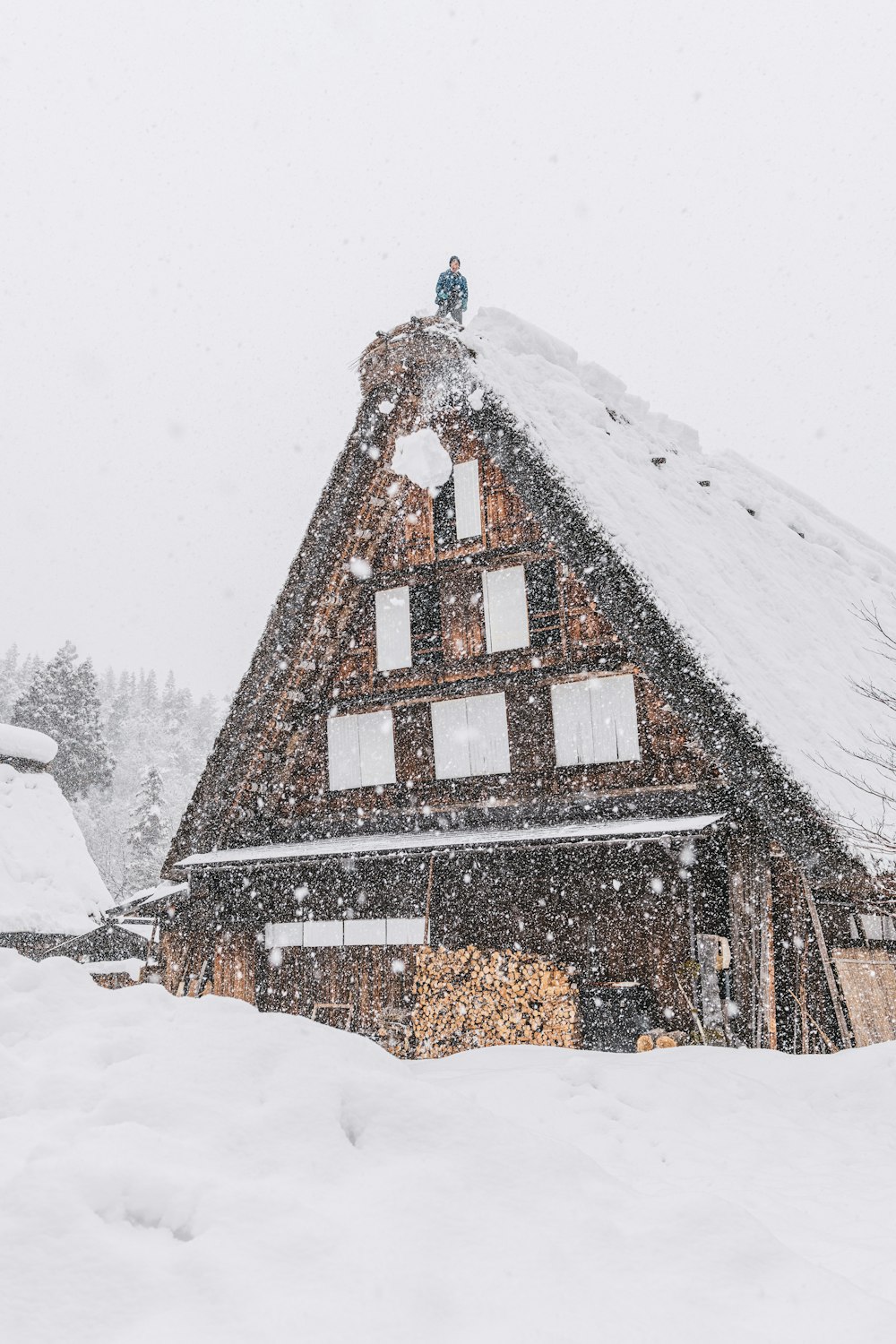 a house covered in snow with a person standing on top of it