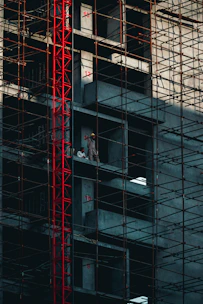 a man standing on a scaffolding in front of a tall building
