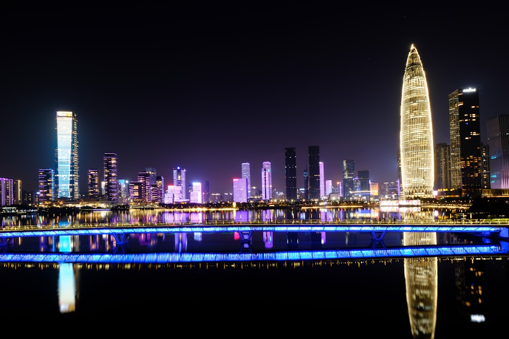 a city skyline at night with a bridge over a body of water