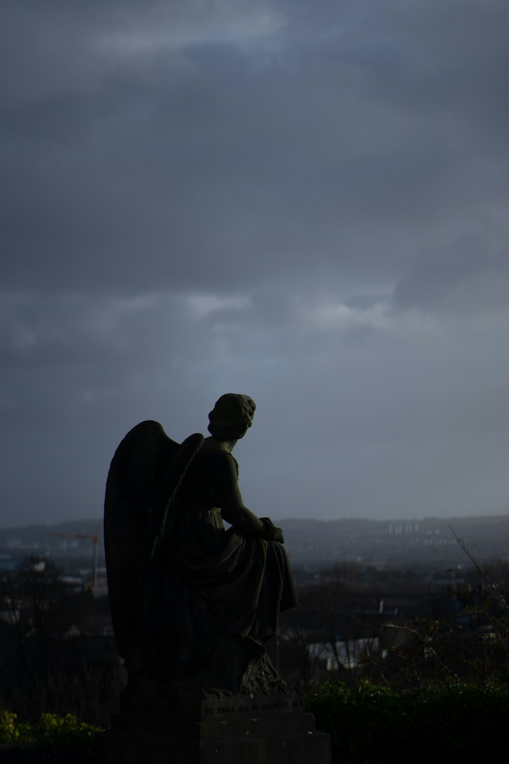 a statue of an angel sitting on top of a hill