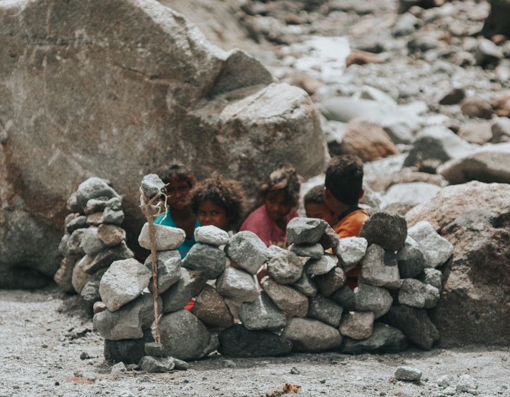 a group of children playing around a pile of rocks