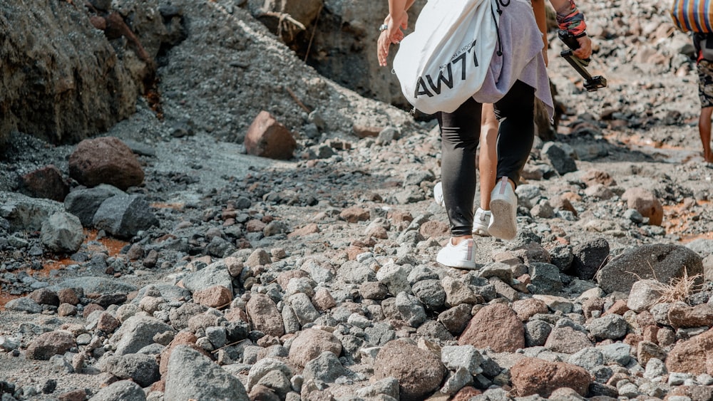 a man walking down a rocky road carrying a bag