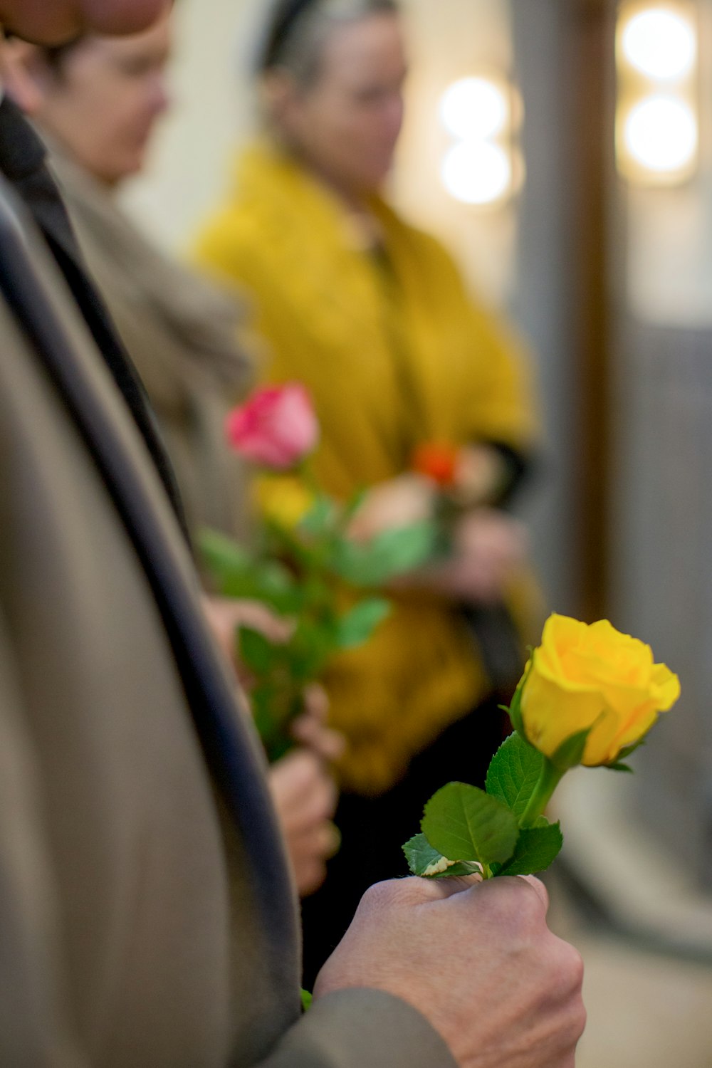 a man holding a yellow rose in his hand