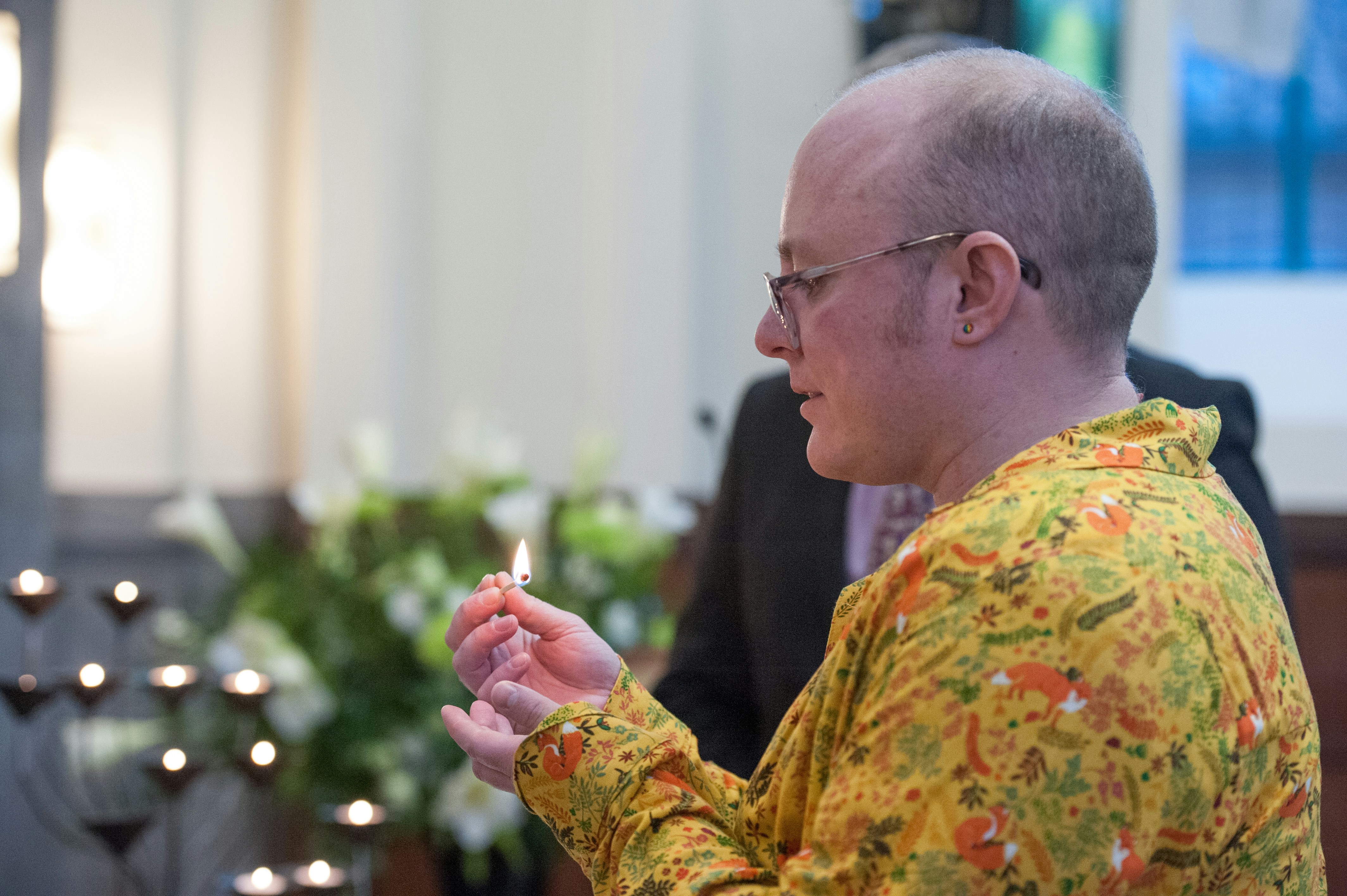 a man in a yellow shirt holding a lit candle