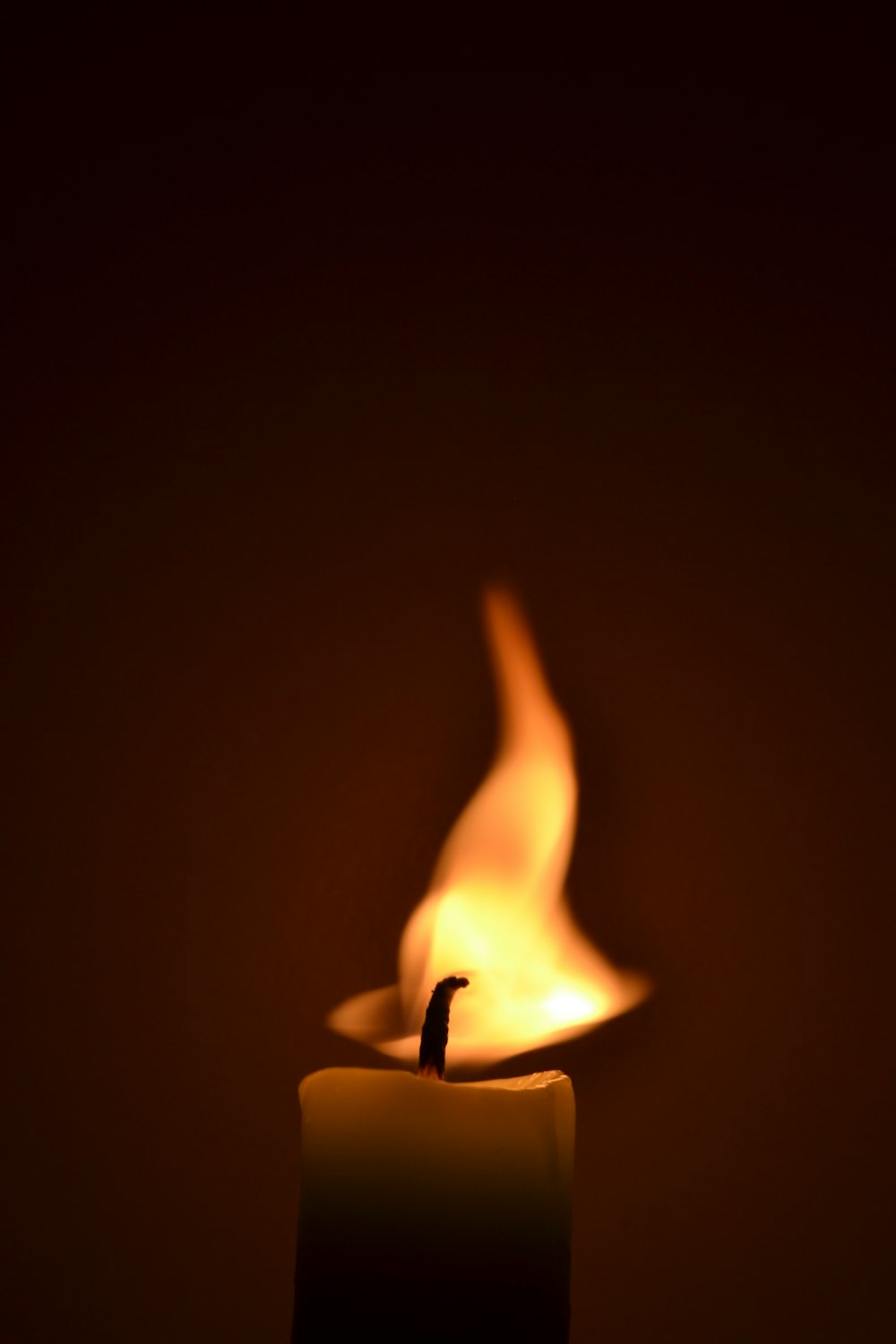 a lit candle with a dark background