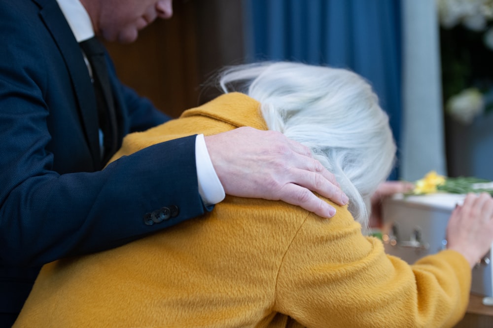 a man and woman hugging each other in front of a cake