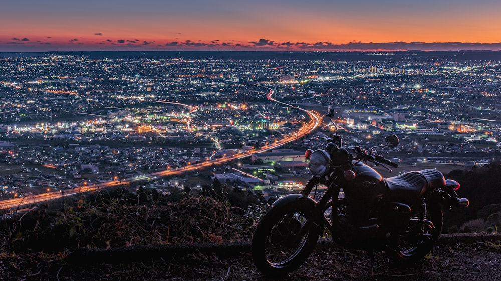 a motorcycle parked on top of a hill overlooking a city