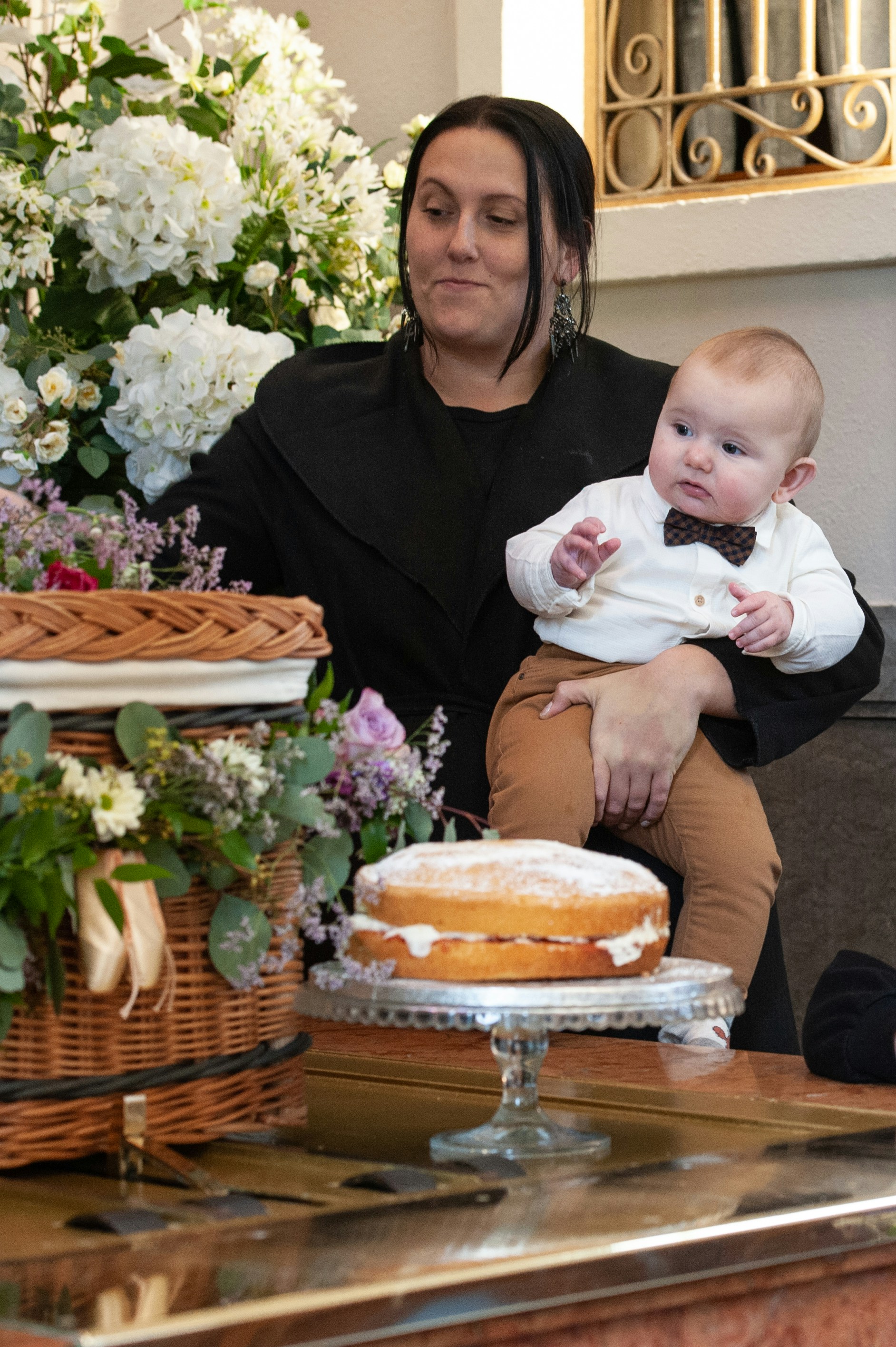 a woman holding a baby in front of a cake