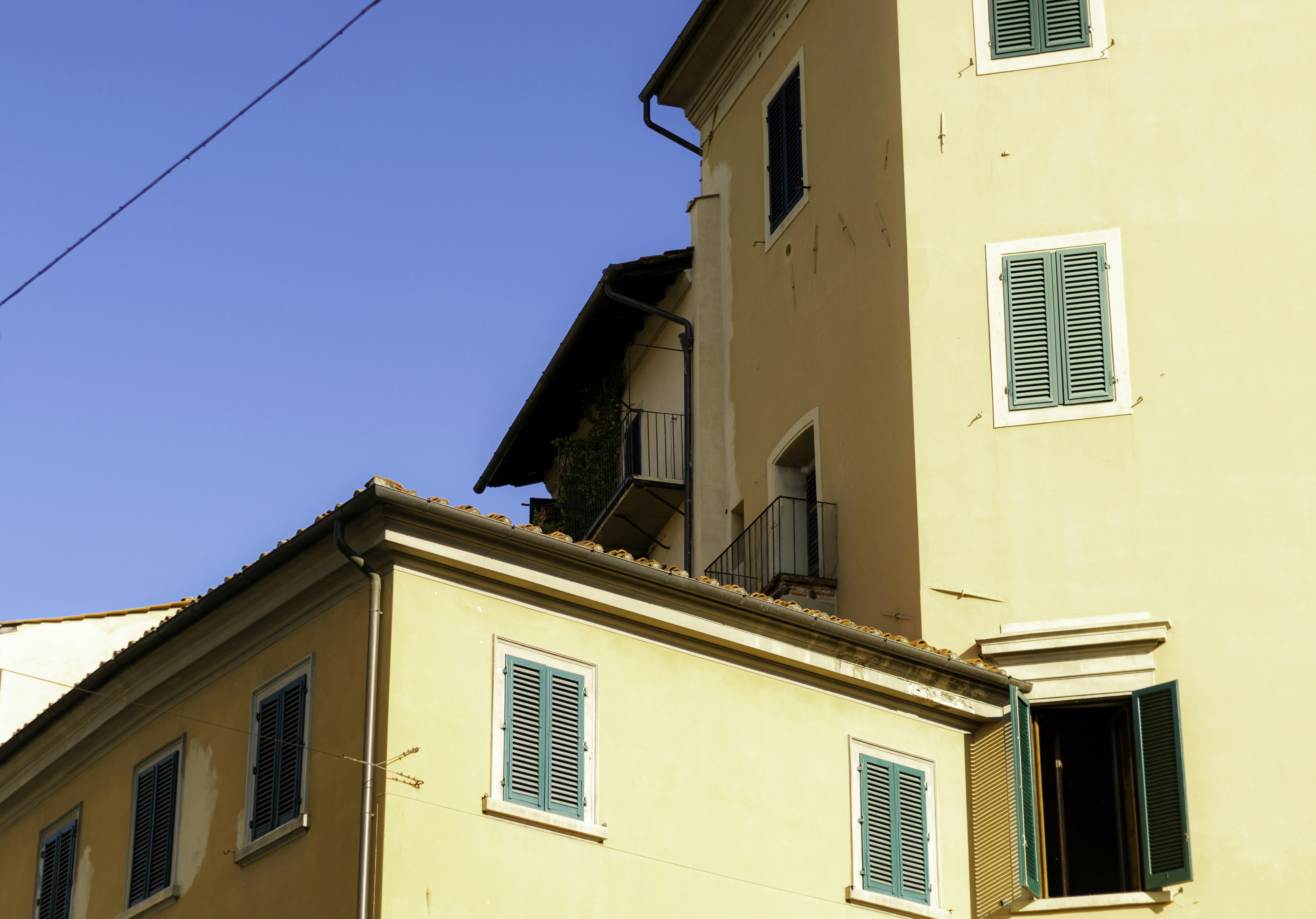 a yellow building with green shutters and a balcony