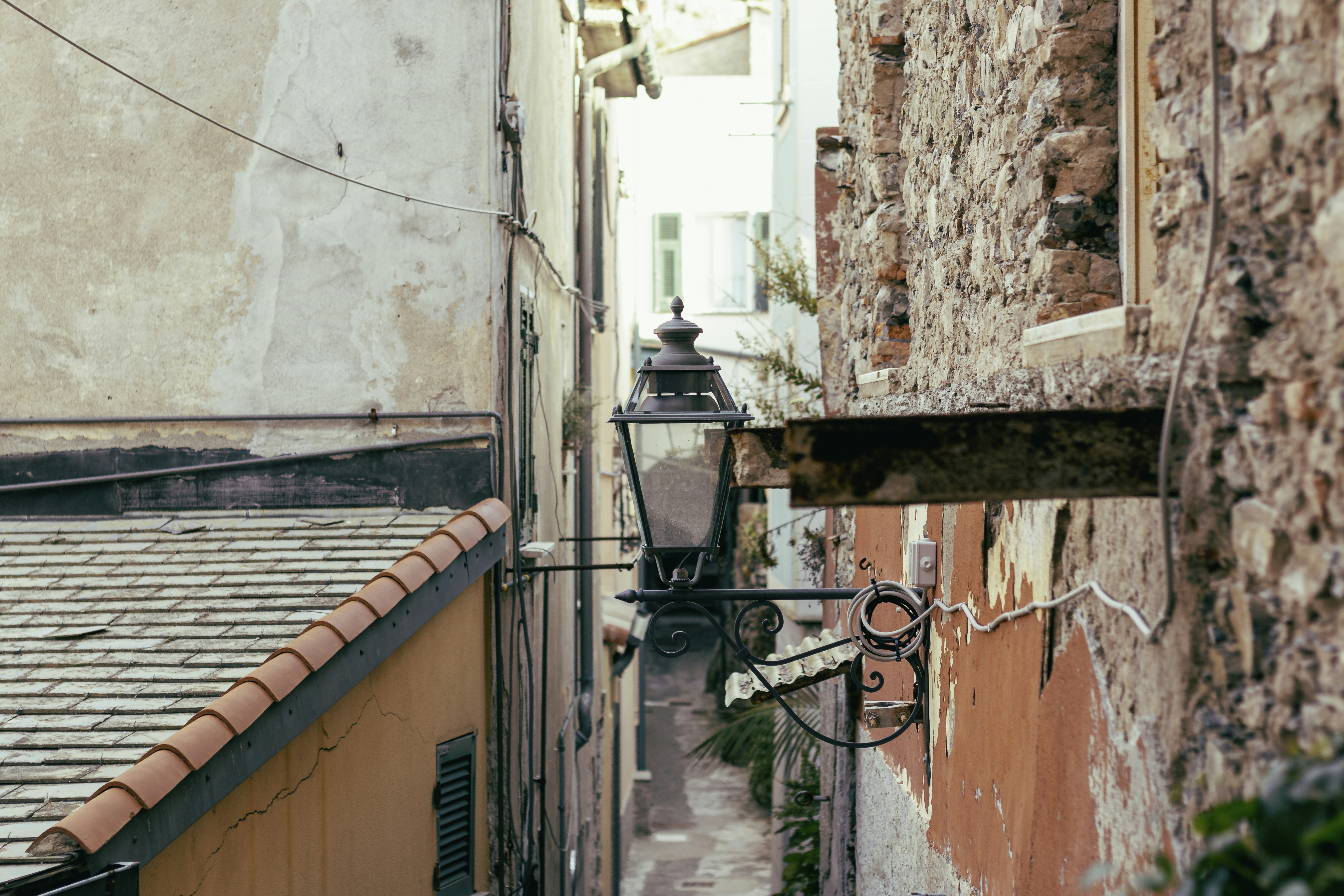 a narrow alley way with a lamp on the side