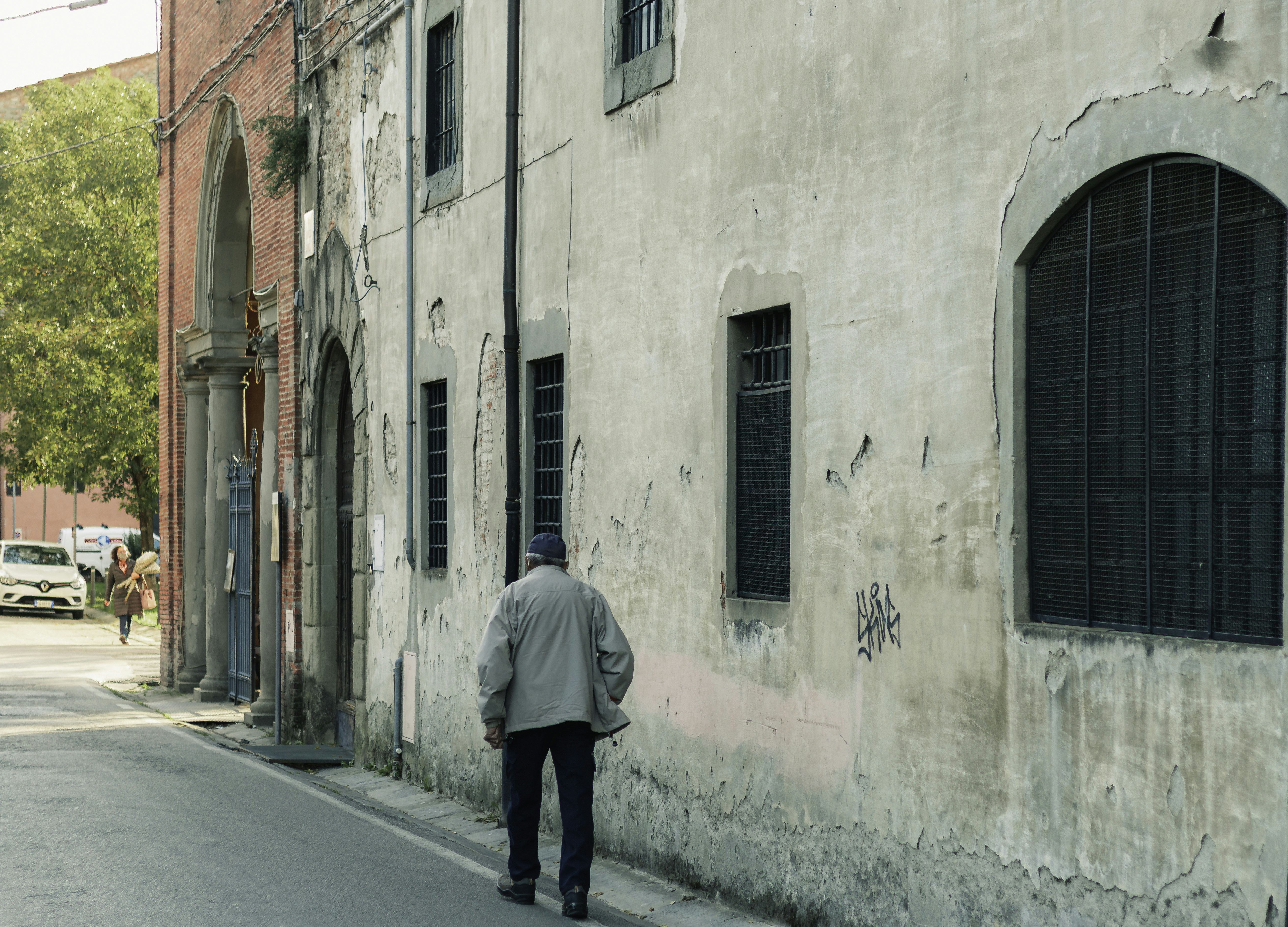 a man walking down a street next to a building