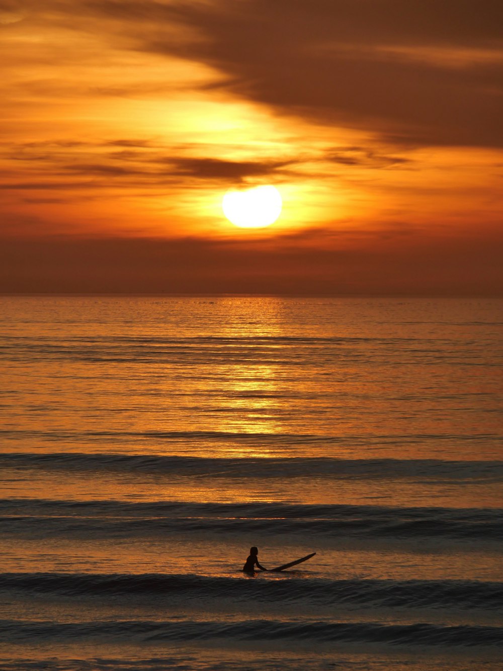 a person on a surfboard in the ocean at sunset