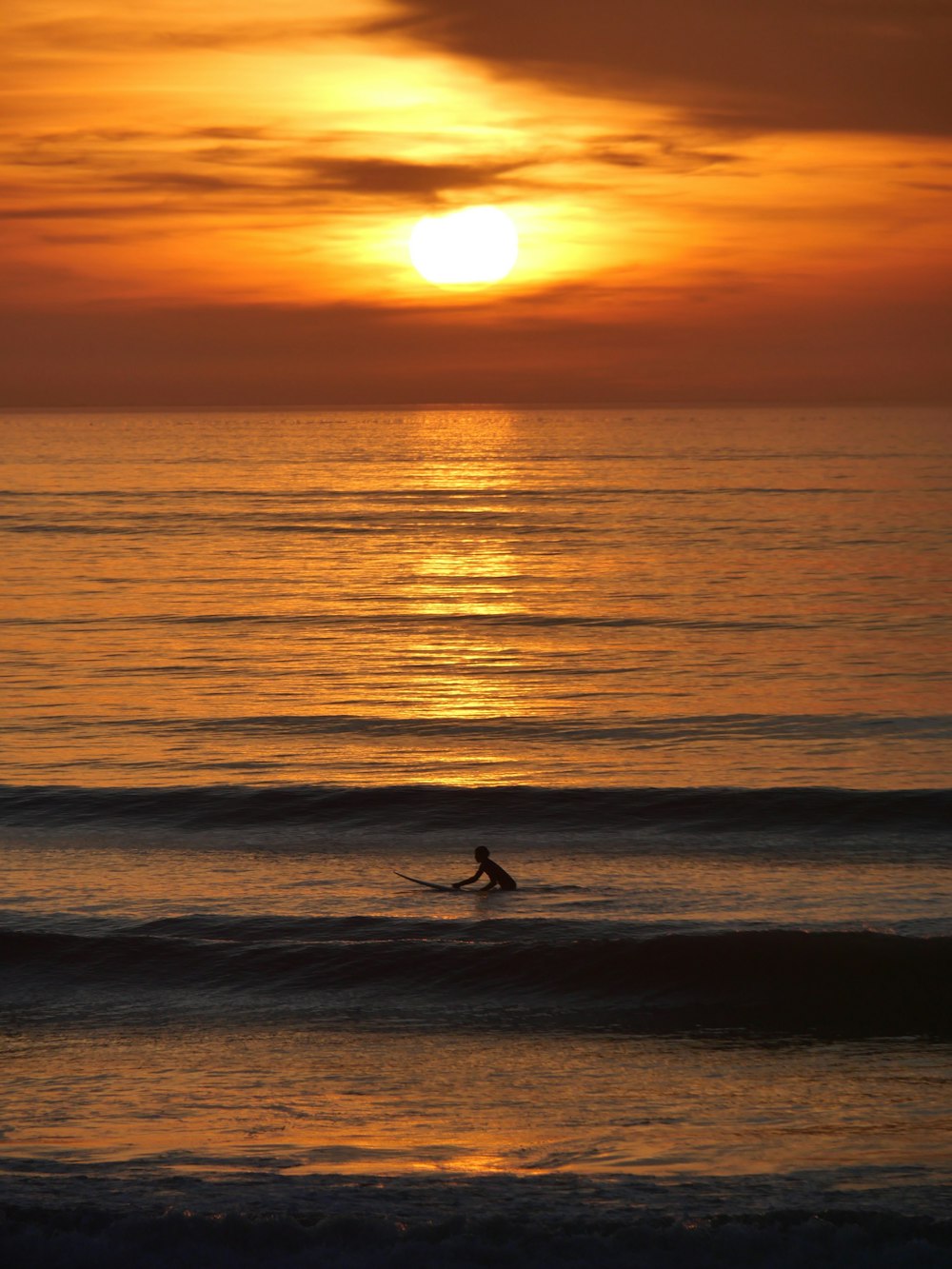 a person riding a surfboard on a wave at sunset