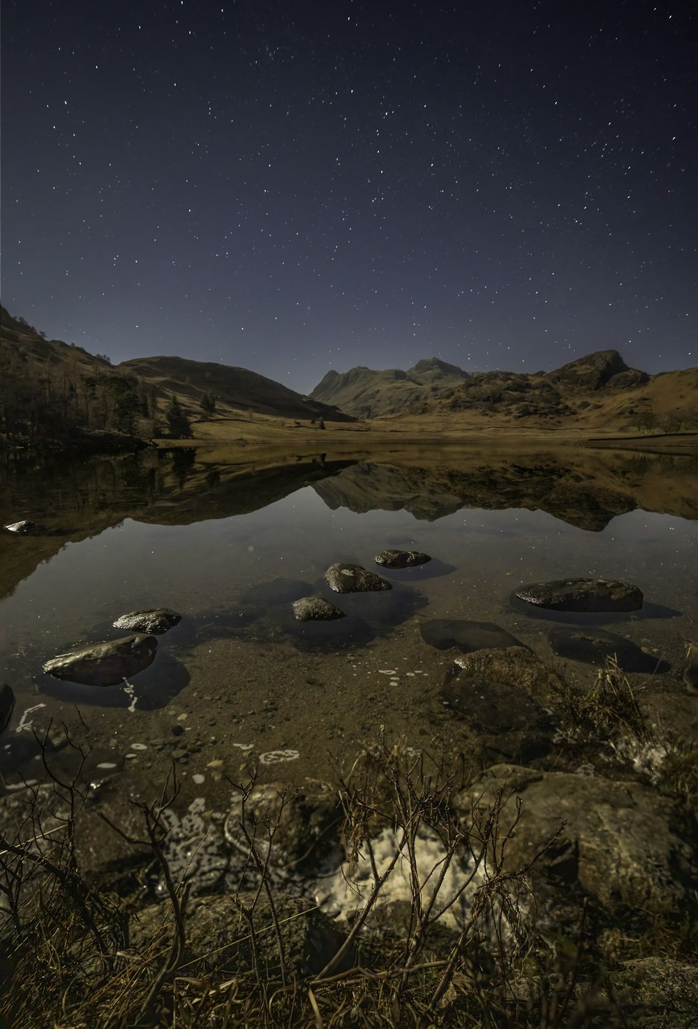 a lake surrounded by mountains under a night sky