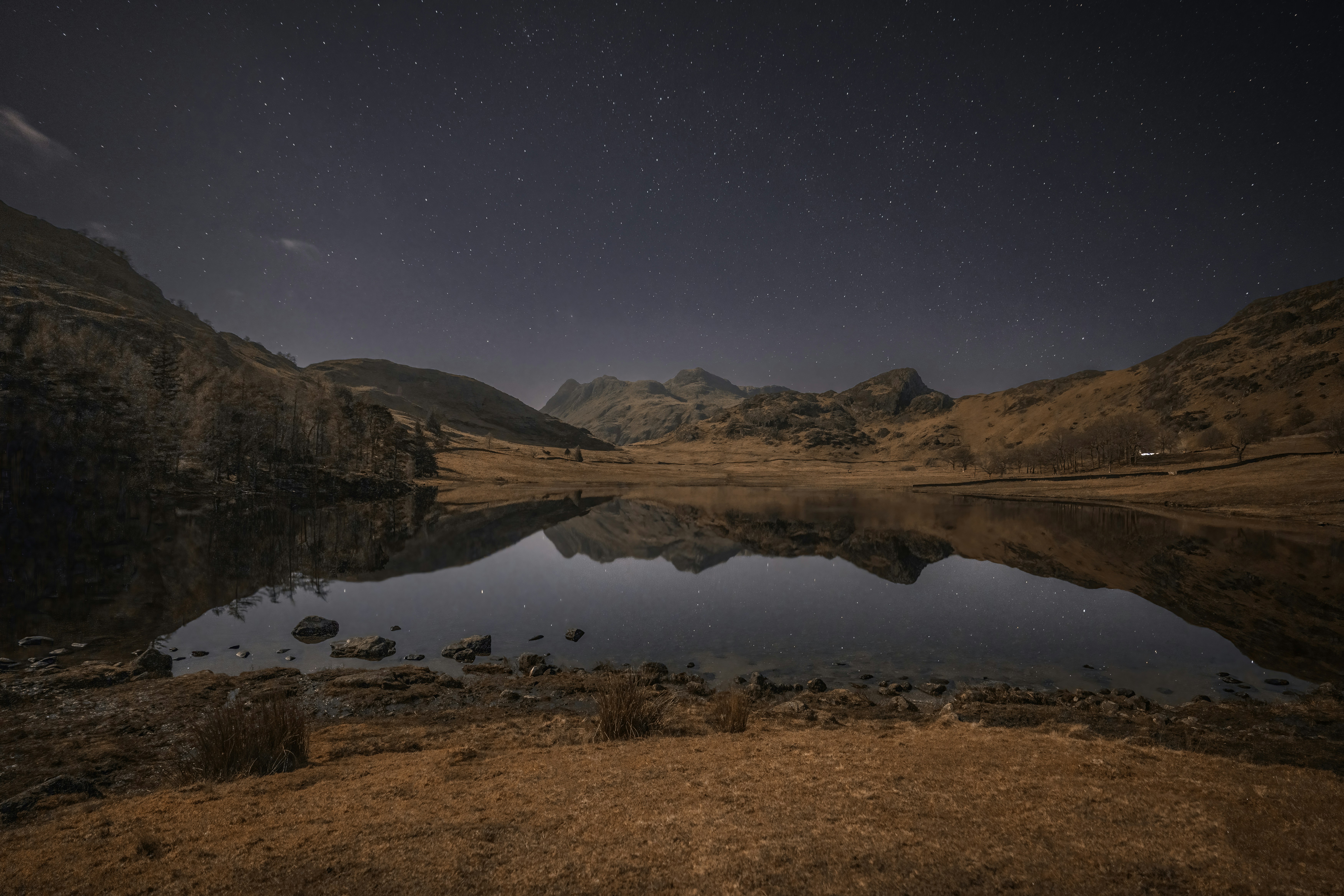 a lake surrounded by mountains under a night sky