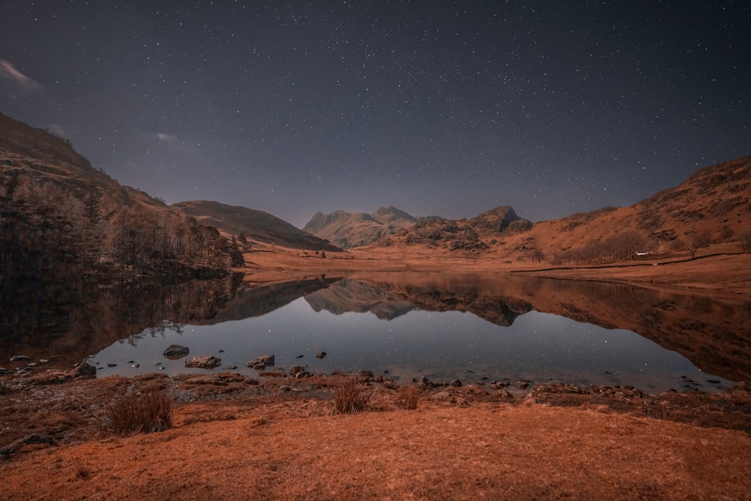 a lake surrounded by mountains under a night sky