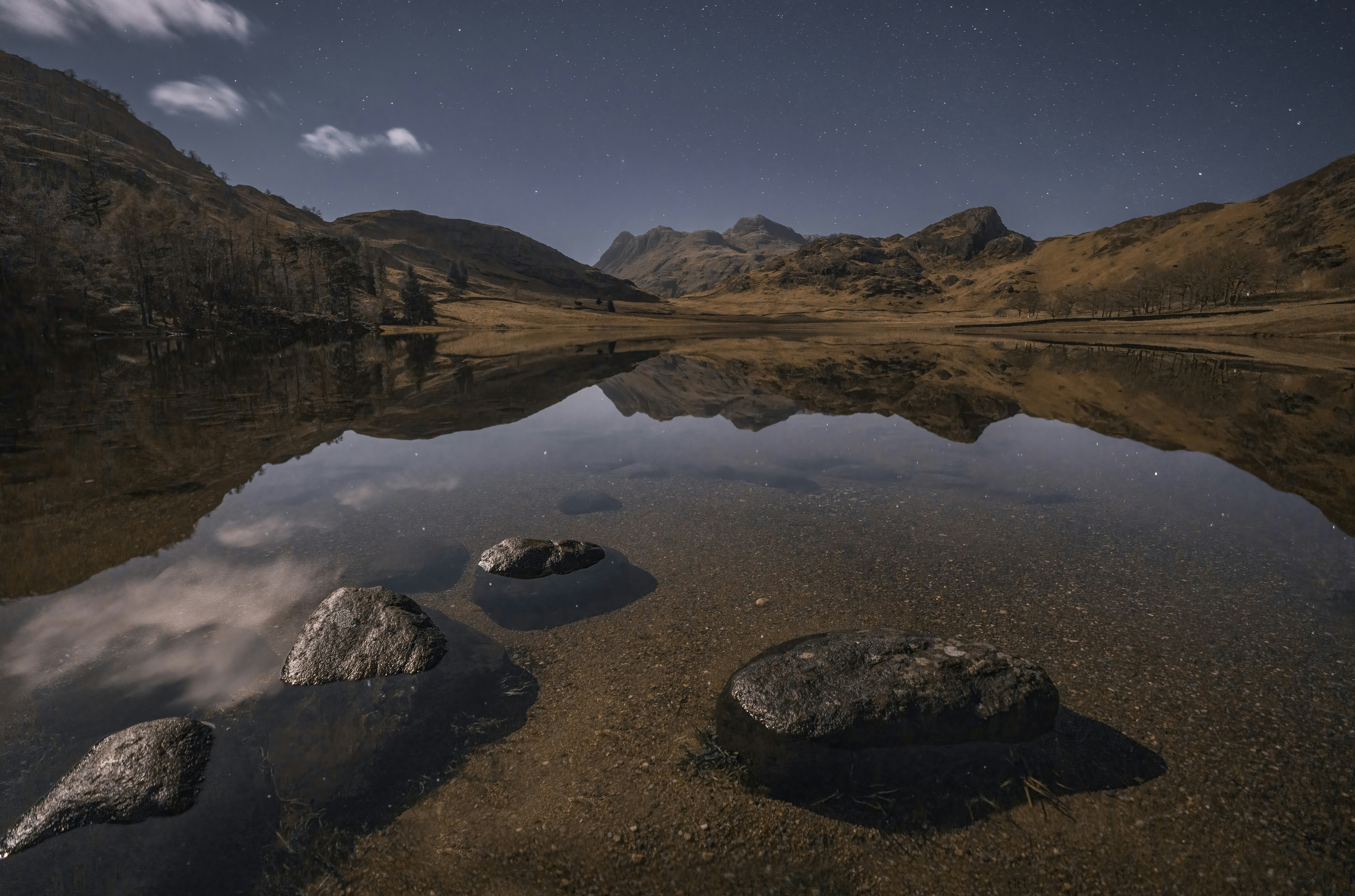 a lake surrounded by mountains under a night sky